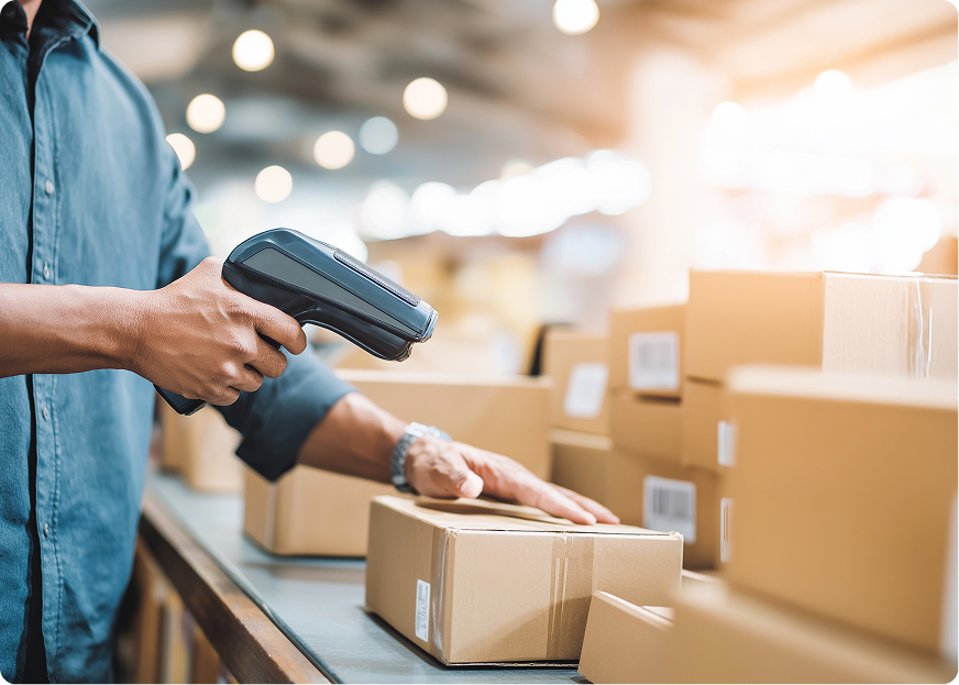Worker scanning parcels on a conveyor in a bright warehouse, illustrating circular reverse logistics and value recovery from returned goods.